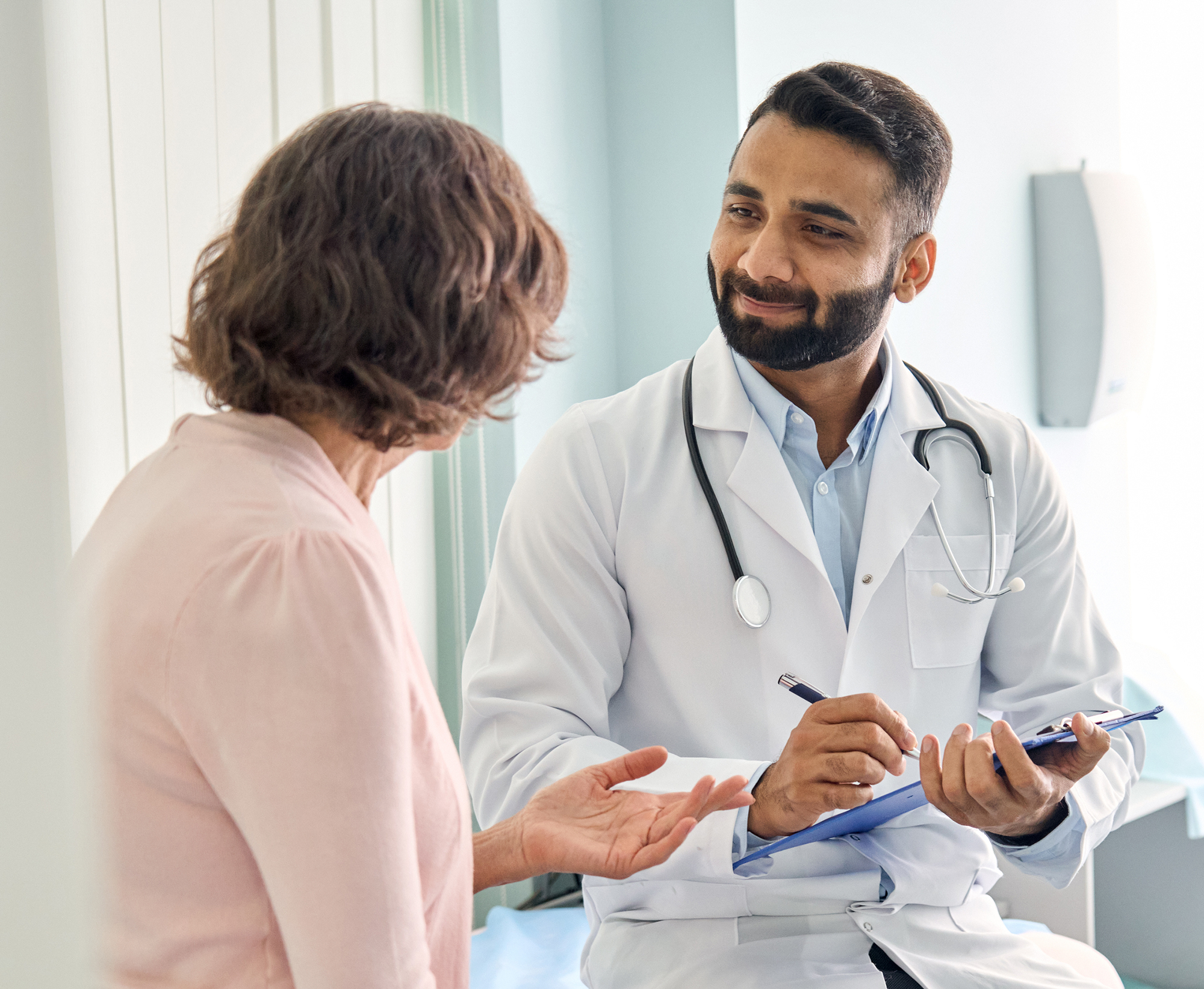 doctor taking patient notes during conversation